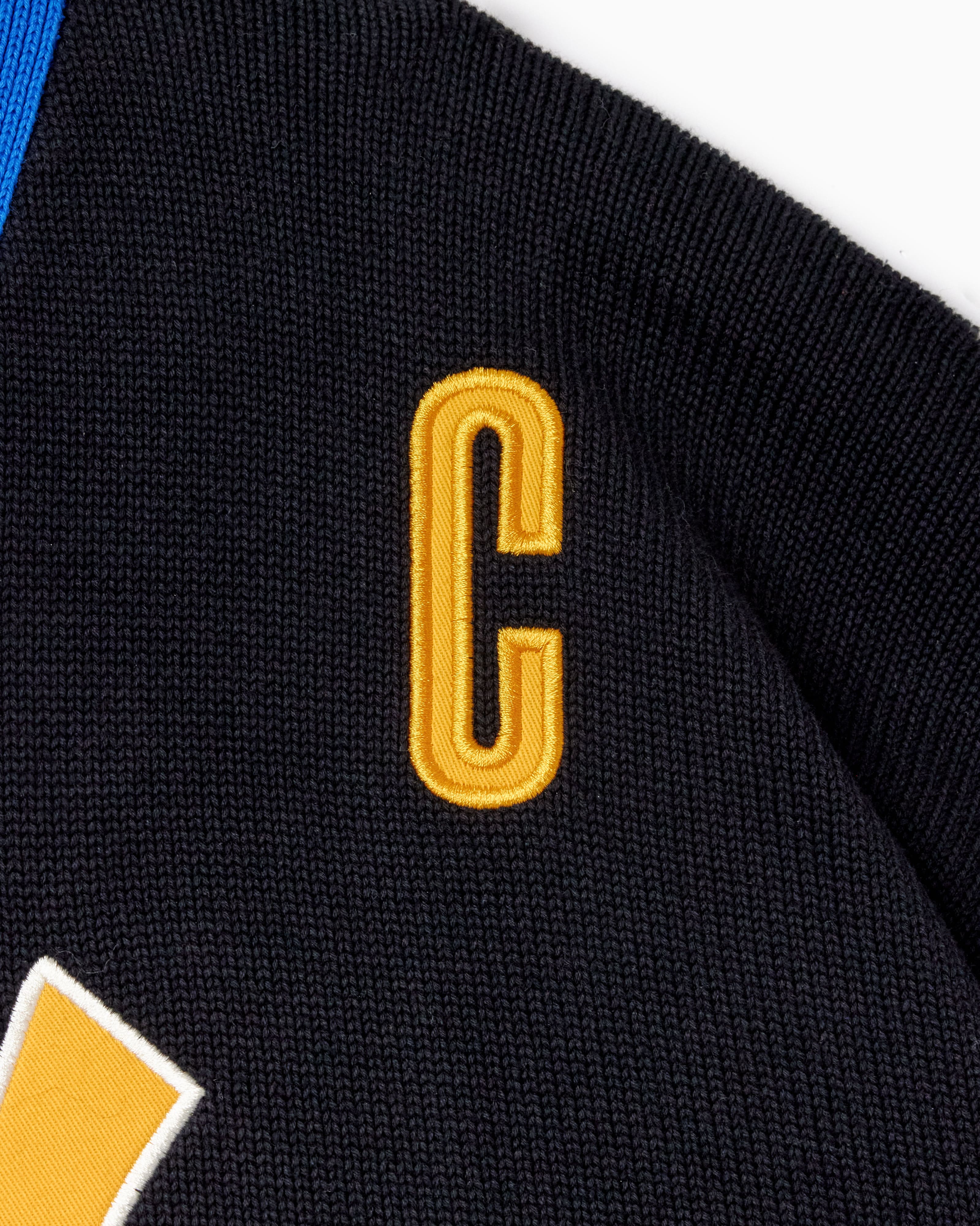 Black sports jersey with a yellow 'C' emblem on a white background