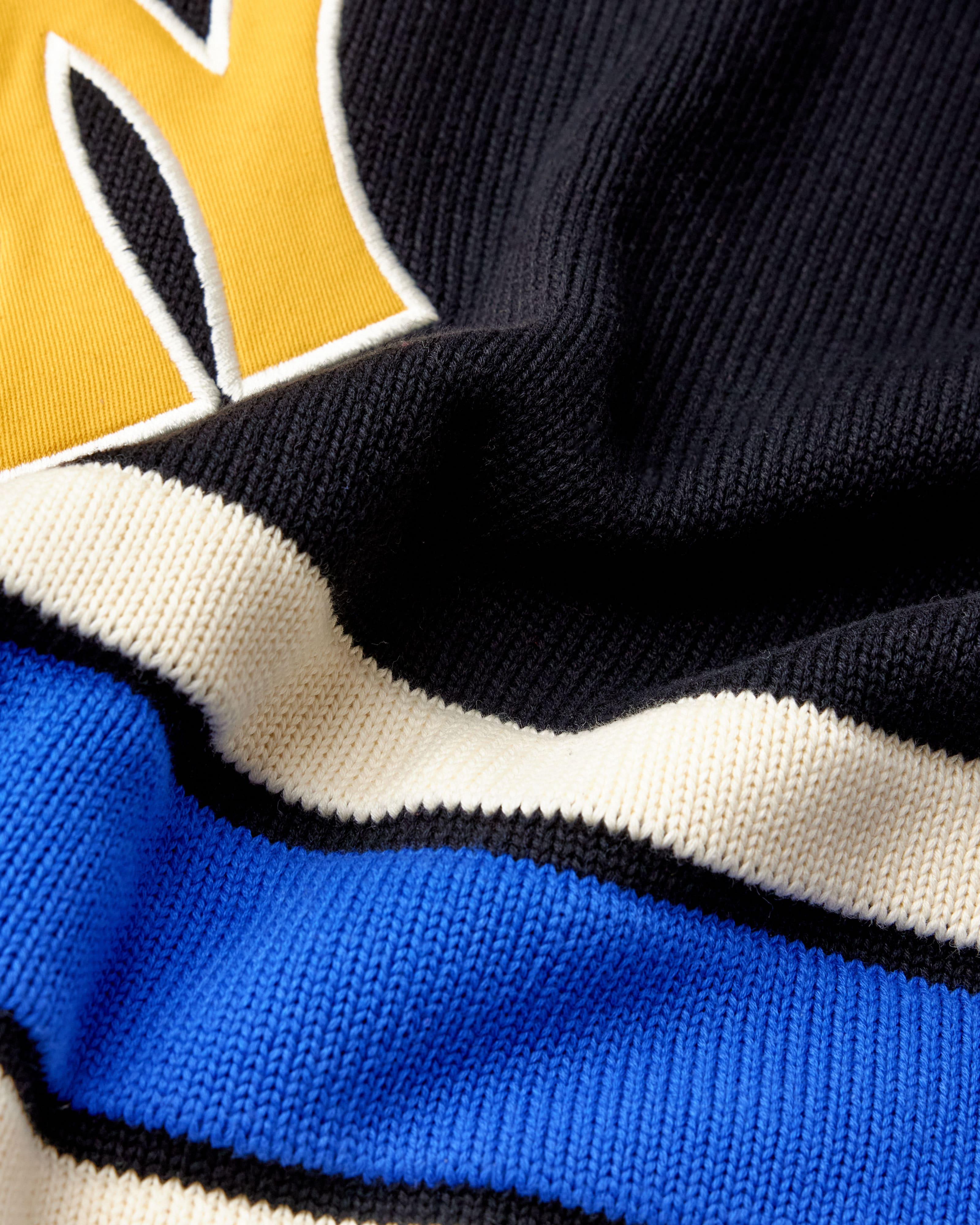 Close-up of a sports jersey with a logo and color-blocked design.