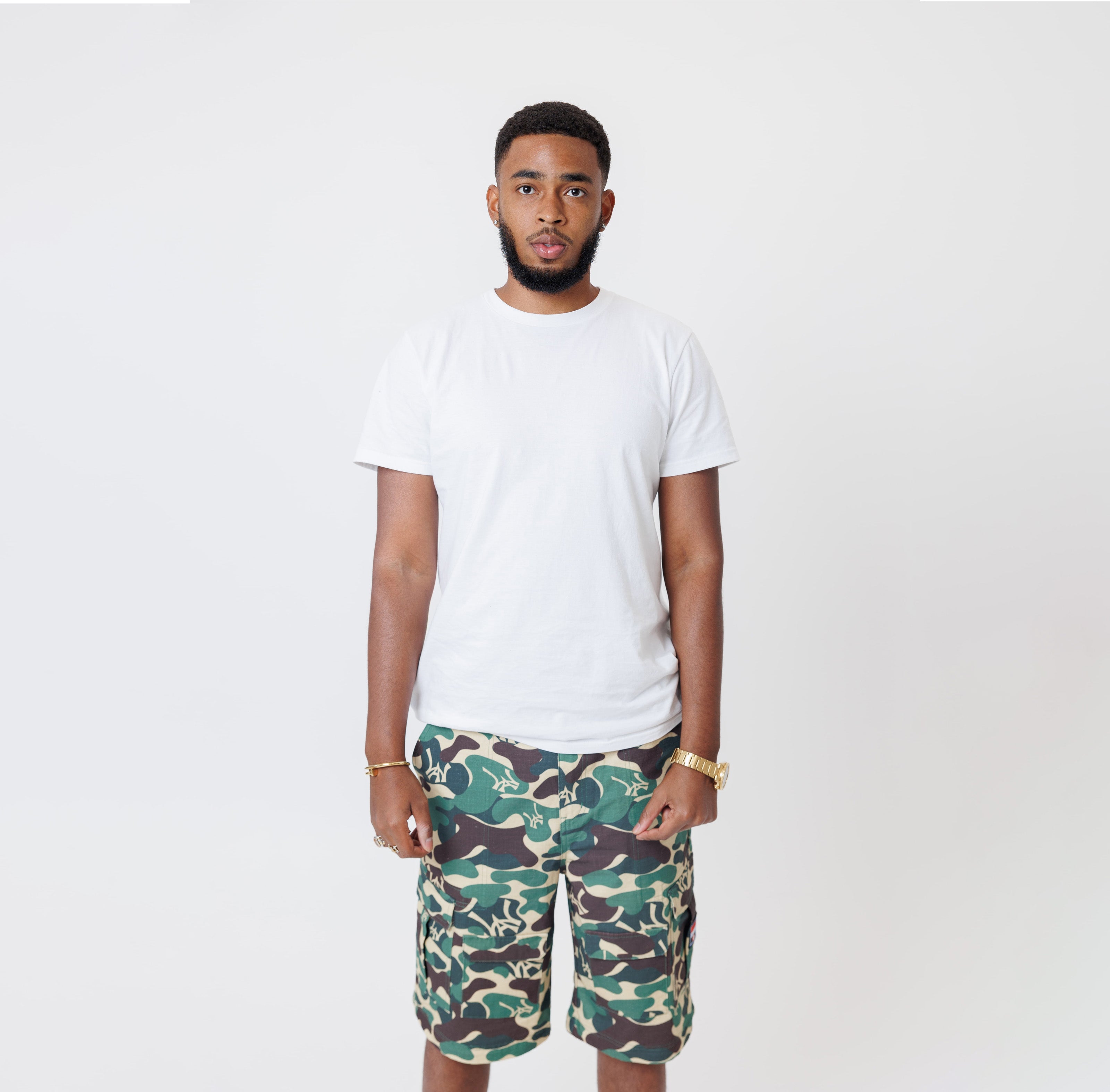 Male Model wearing a white t-shirt and the WOA convertible Cargo shorts in Camo color on a white background.
