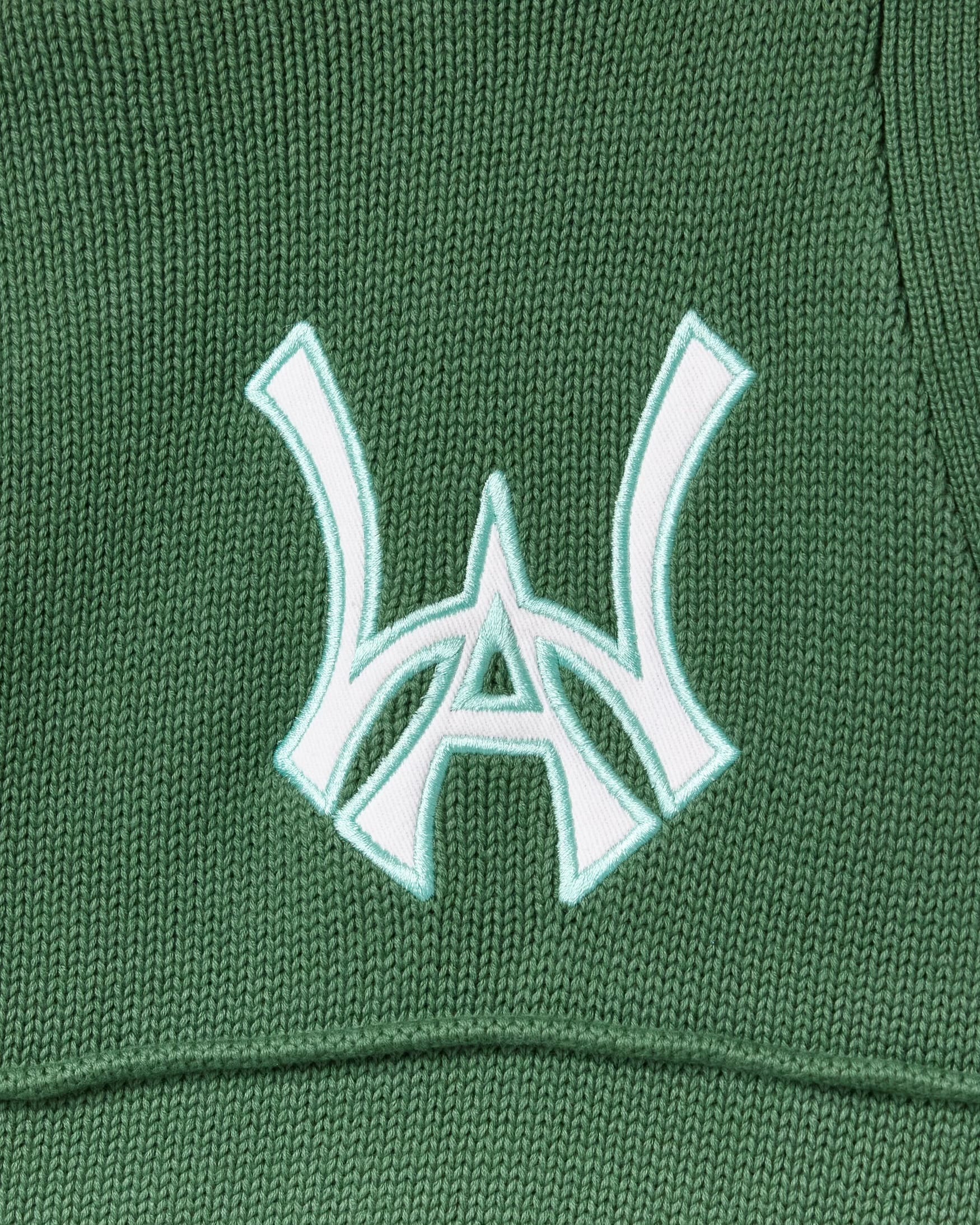 Close-up of a sage green fabric with a white WA logo on a textured background