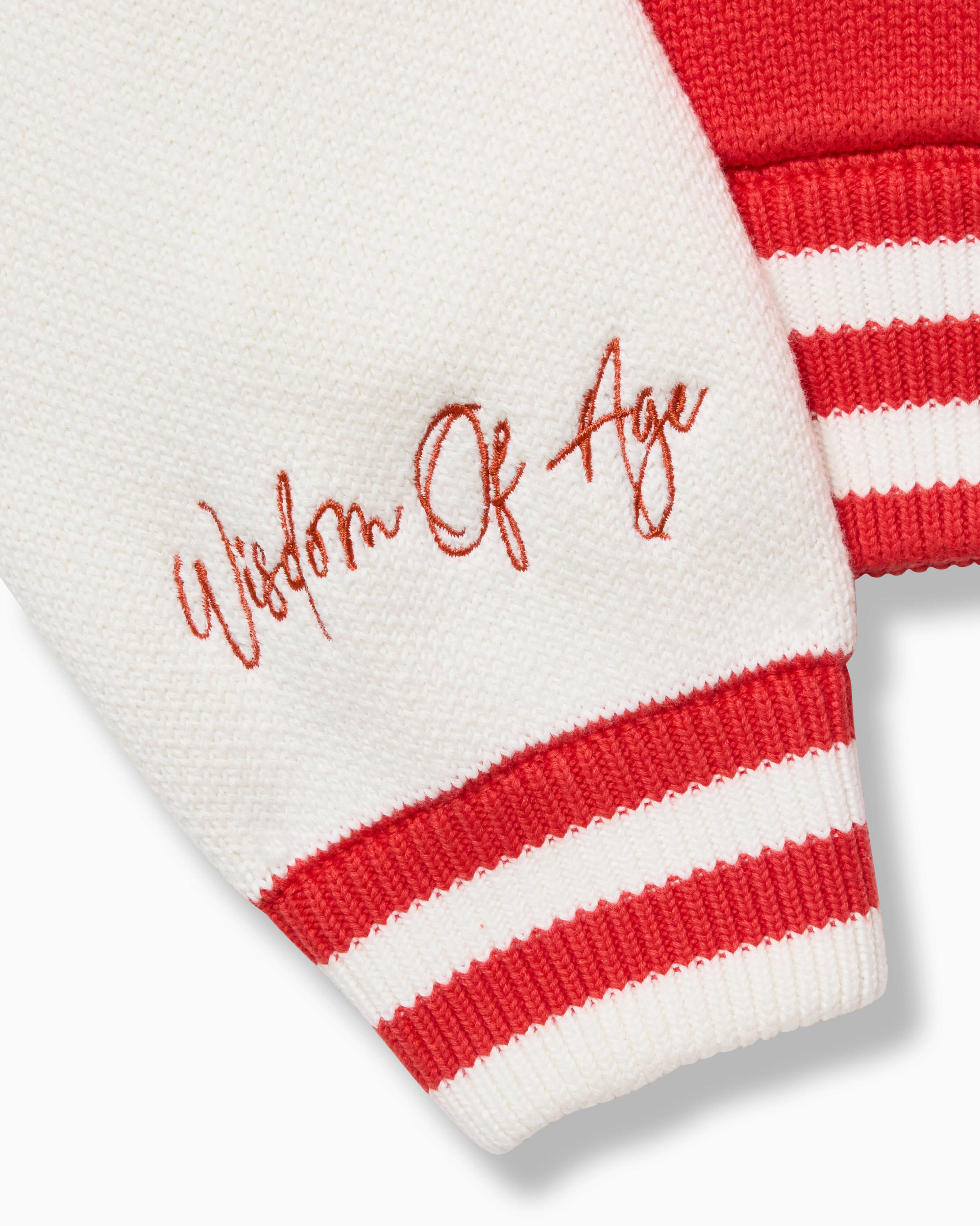 Closer look at the right sleeve with the brand name "Wisdom of Age" embroidered in a handwritten script cursive above the cuff hem.