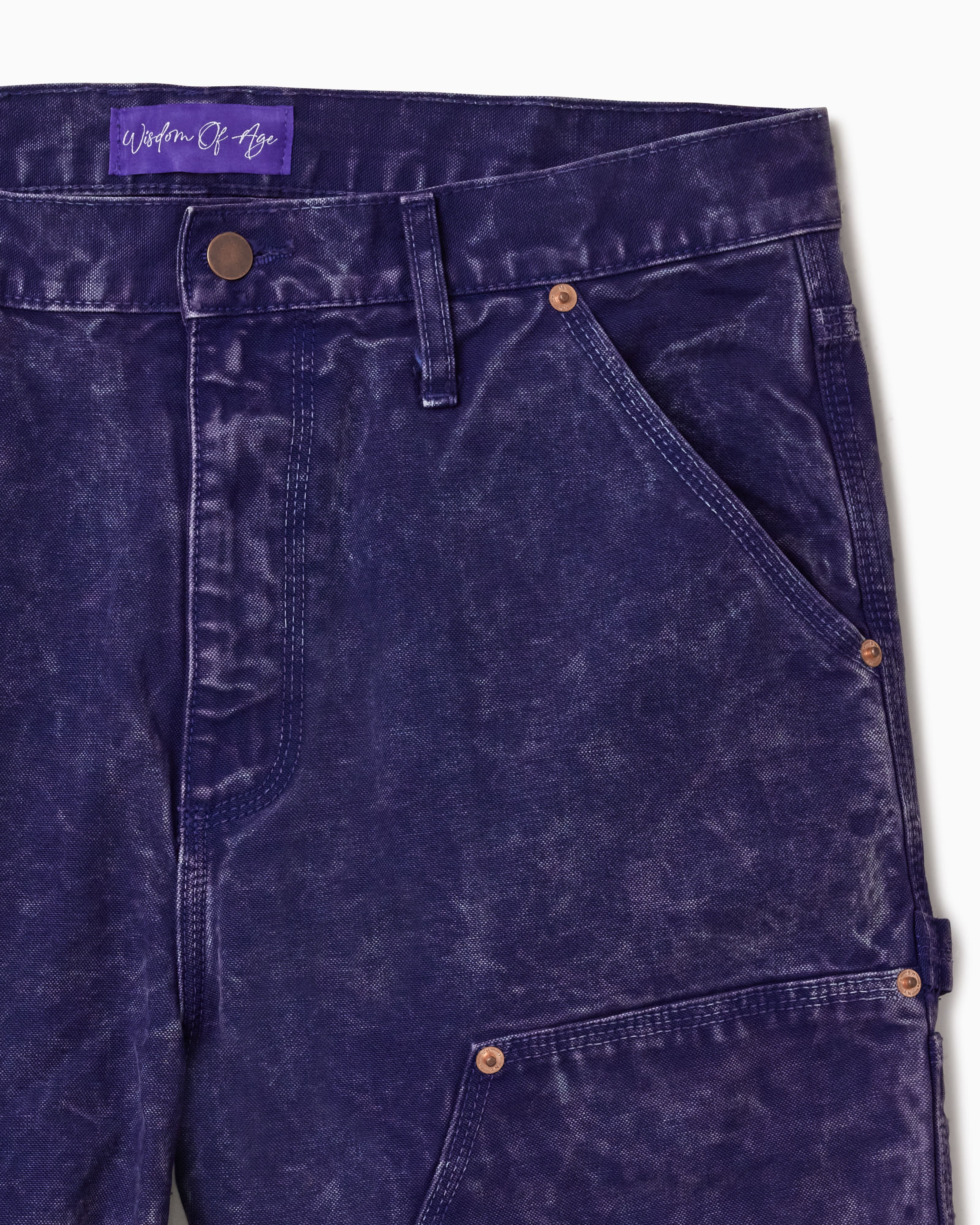Close Up Of WOA Canvas Carpenter Shorts in Purple with WOA brand label on a white background