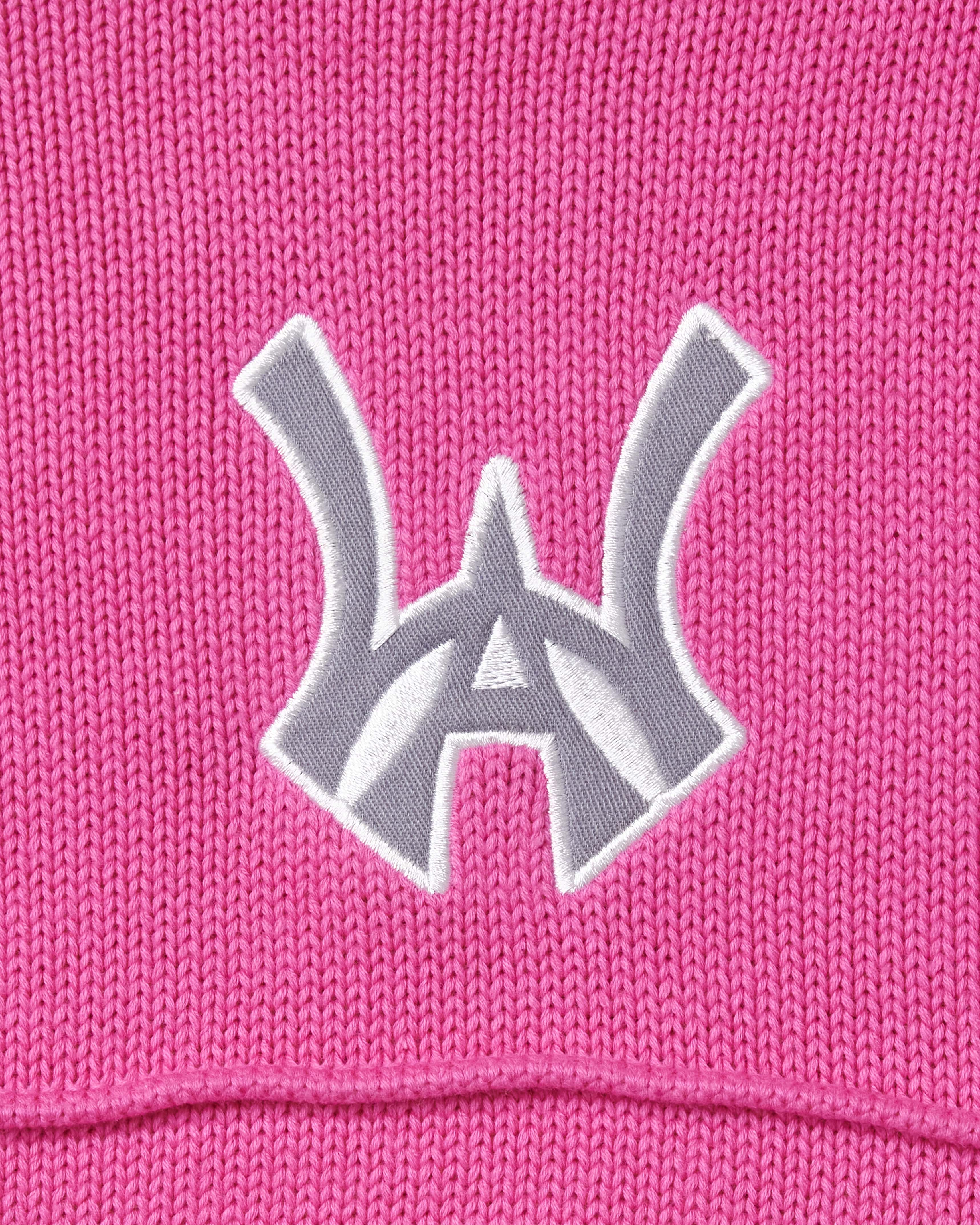 Close-up of the embroidered WA logo on a pink background