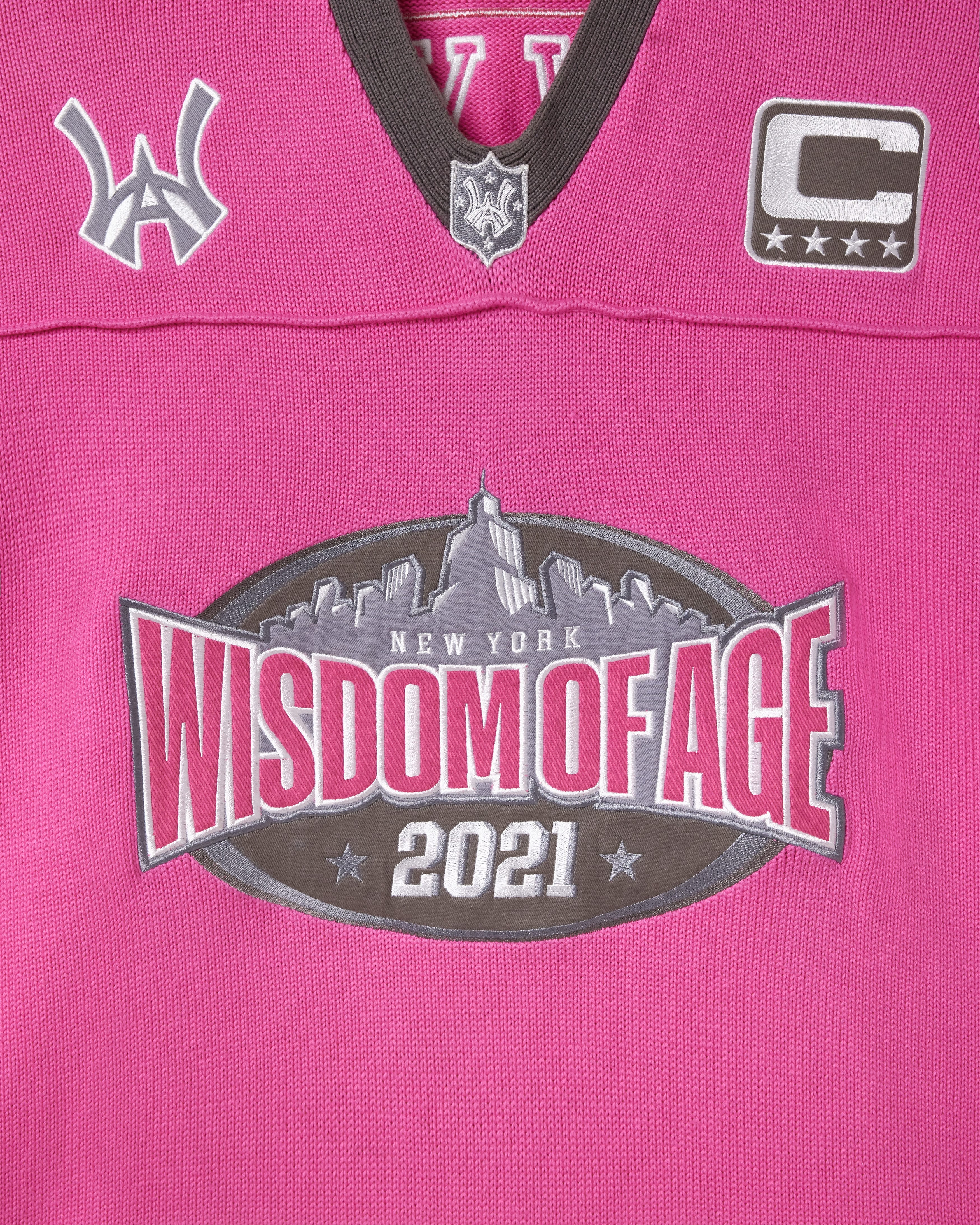 Pink knitted football jersey with Wisdom Of Age logos.