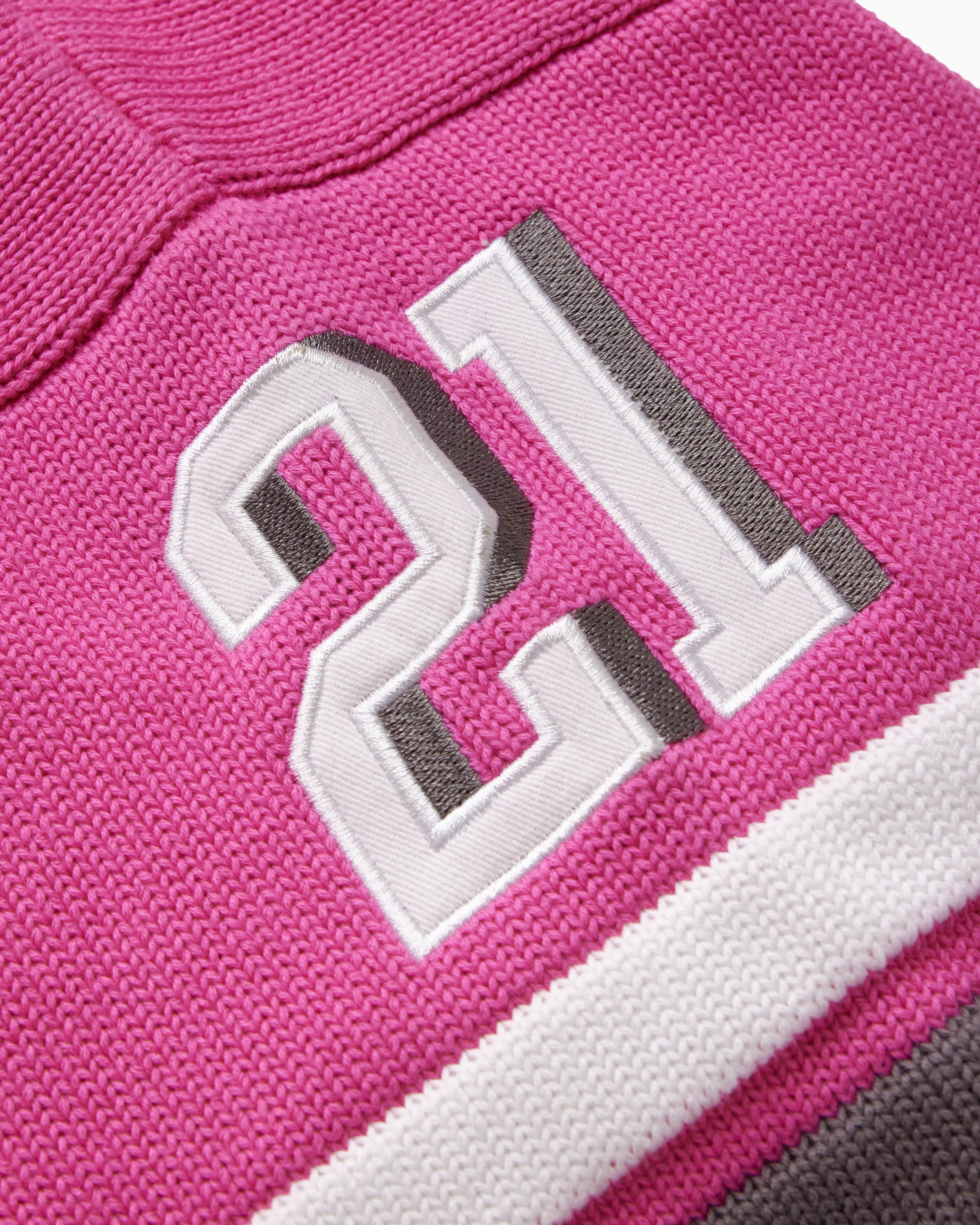 Close-up of the wisdom of age pink knitted football jersey with the number 21 on it.