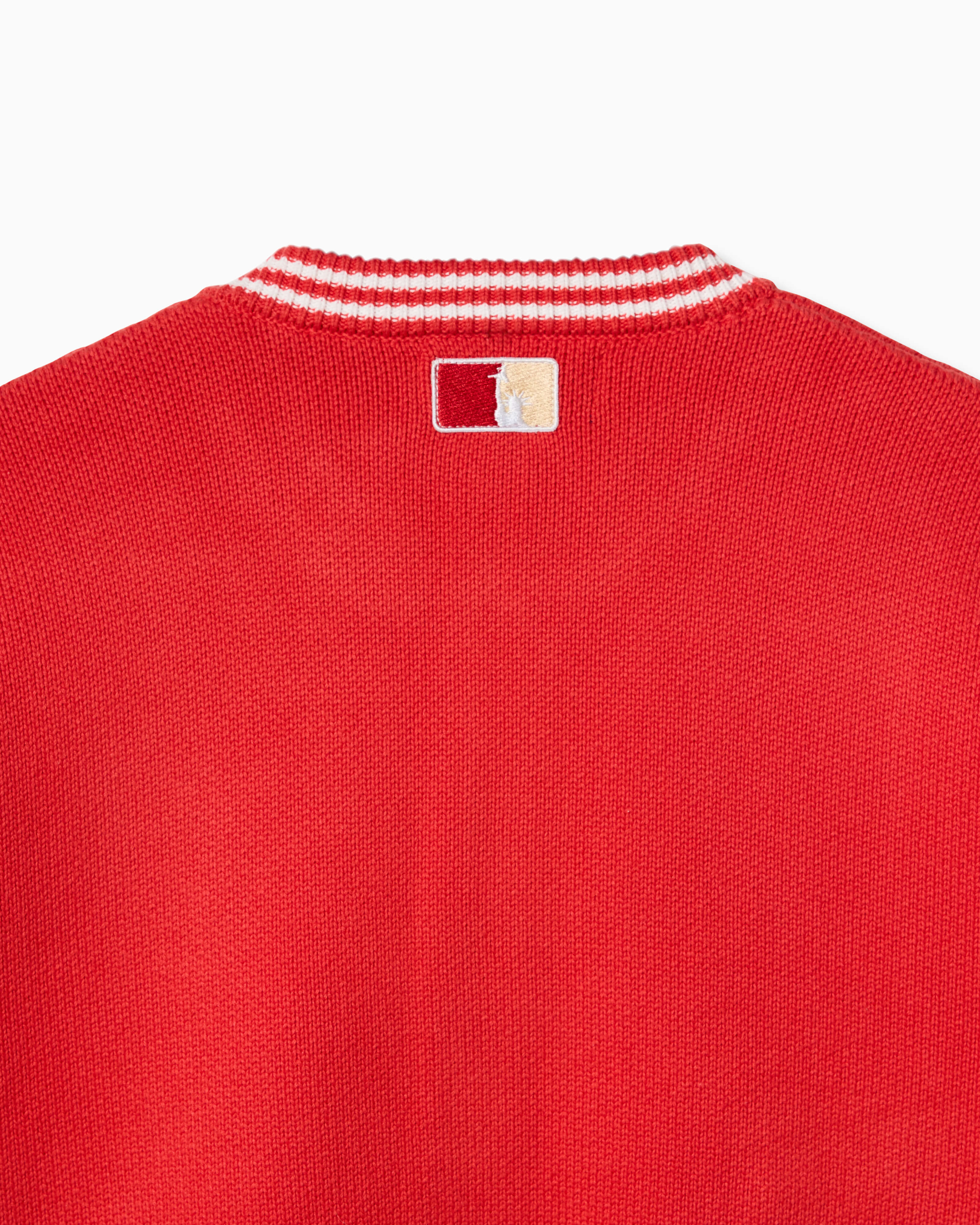 Closer look at the back of the cardigan with an embroidered square patch below the nape of the neck and collar. The patch contains the upper half of the Statue of Liberty in a "NY Tough" inspired logo.