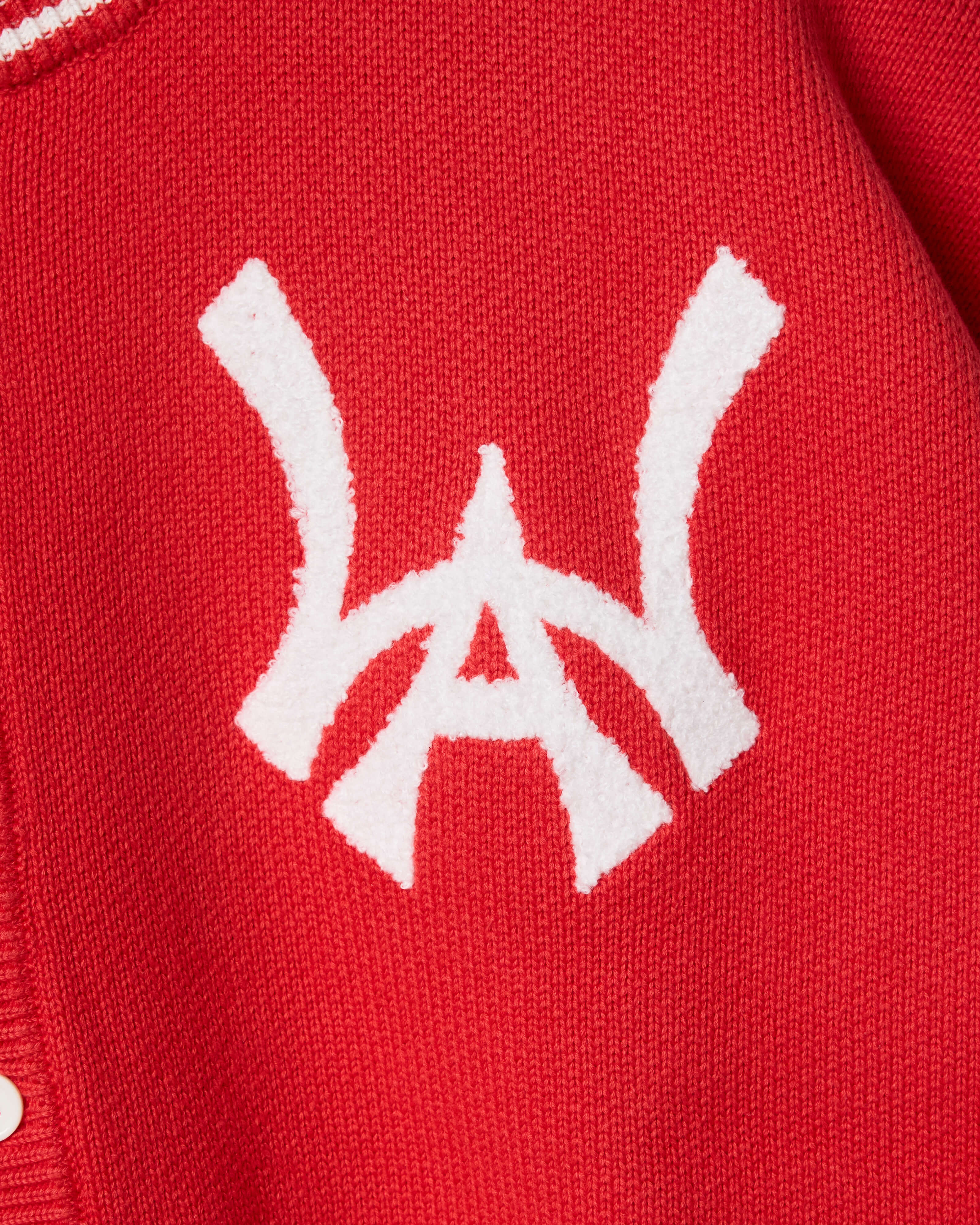 Closer look at the brand logo in a monogram font of connecting the "W" and "A" located on the upper left chest of the cardigan.