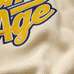 Close-up of a textured fabric with 'Wisdom Of Age' logo in yellow and blue.