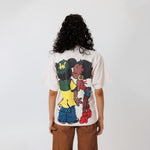 Female model wearing a off-white t-shirt with cartoon characters and brown shorts on a light gray background