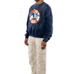 Side view of a Male Model wearing a navy sweatshirt with a logo and beige cargo pants on a white background