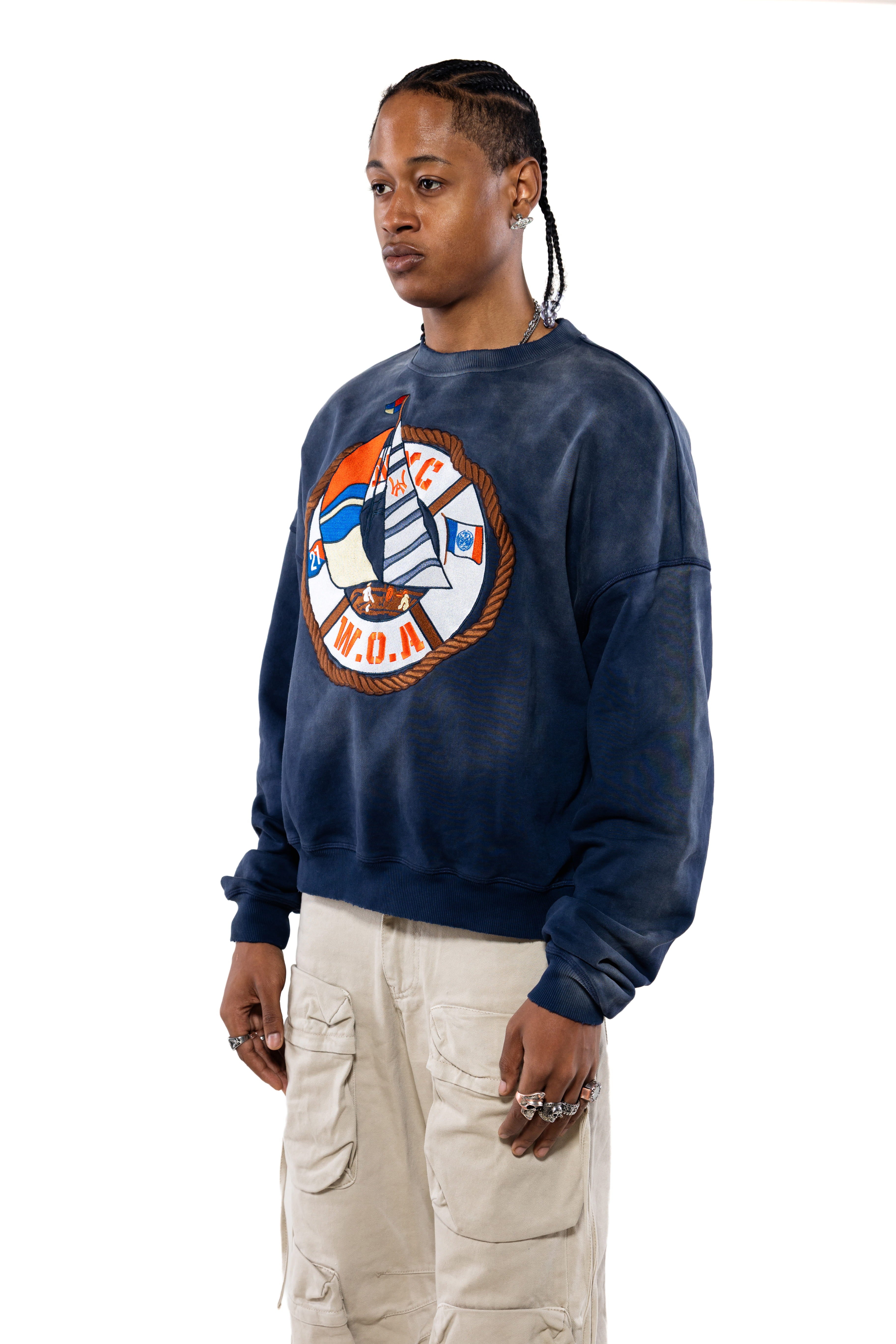 Side close view Male Model wearing a navy sweatshirt with a logo and beige cargo pants on a white background