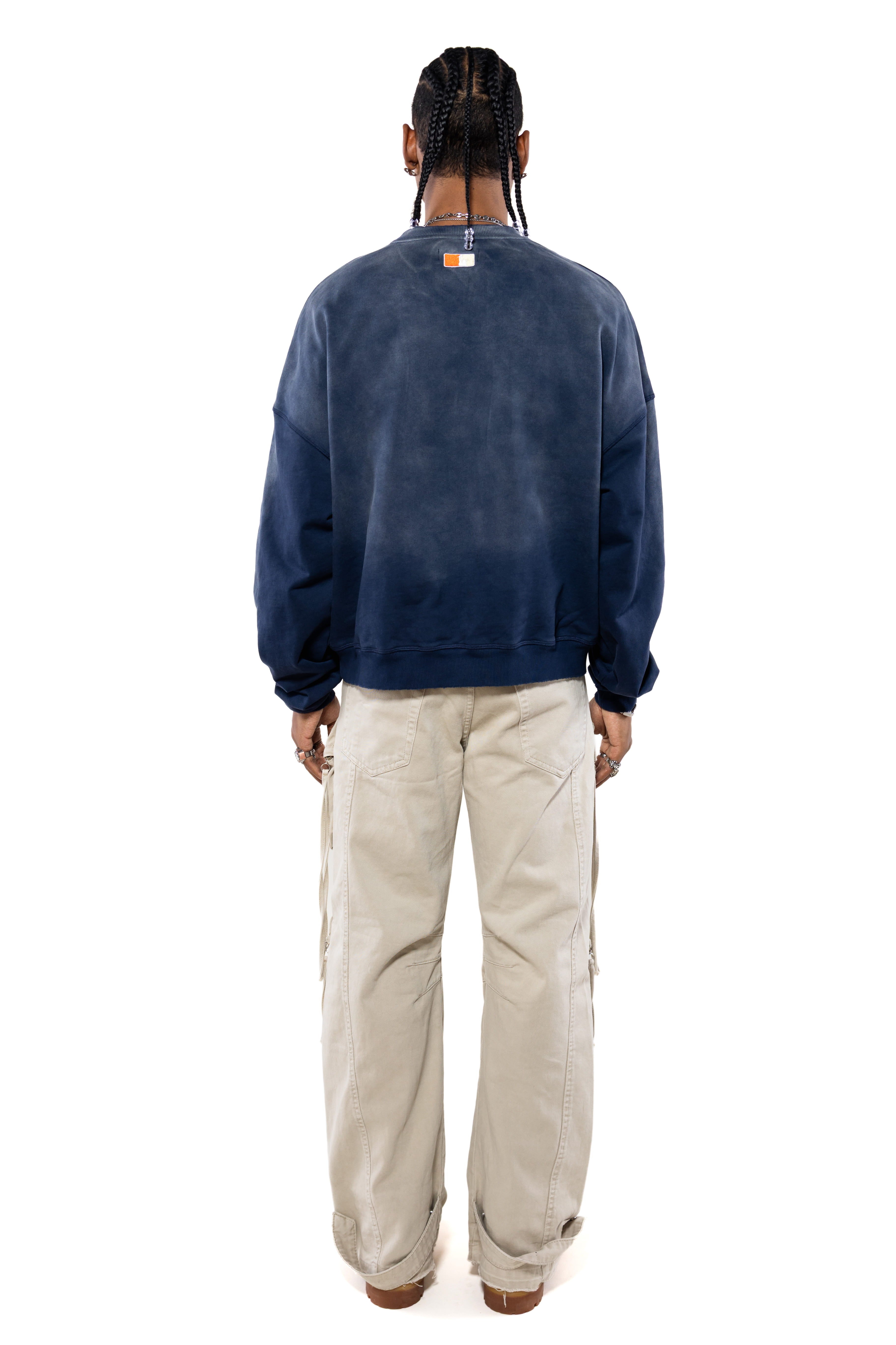 Rear view Male Model wearing a navy sweatshirt with the 'NY Tough' logo on the neck and beige cargo pants on a white background