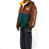 Side view of a Male Model wearing a brown and forest green jacket with yellow accents on a white background