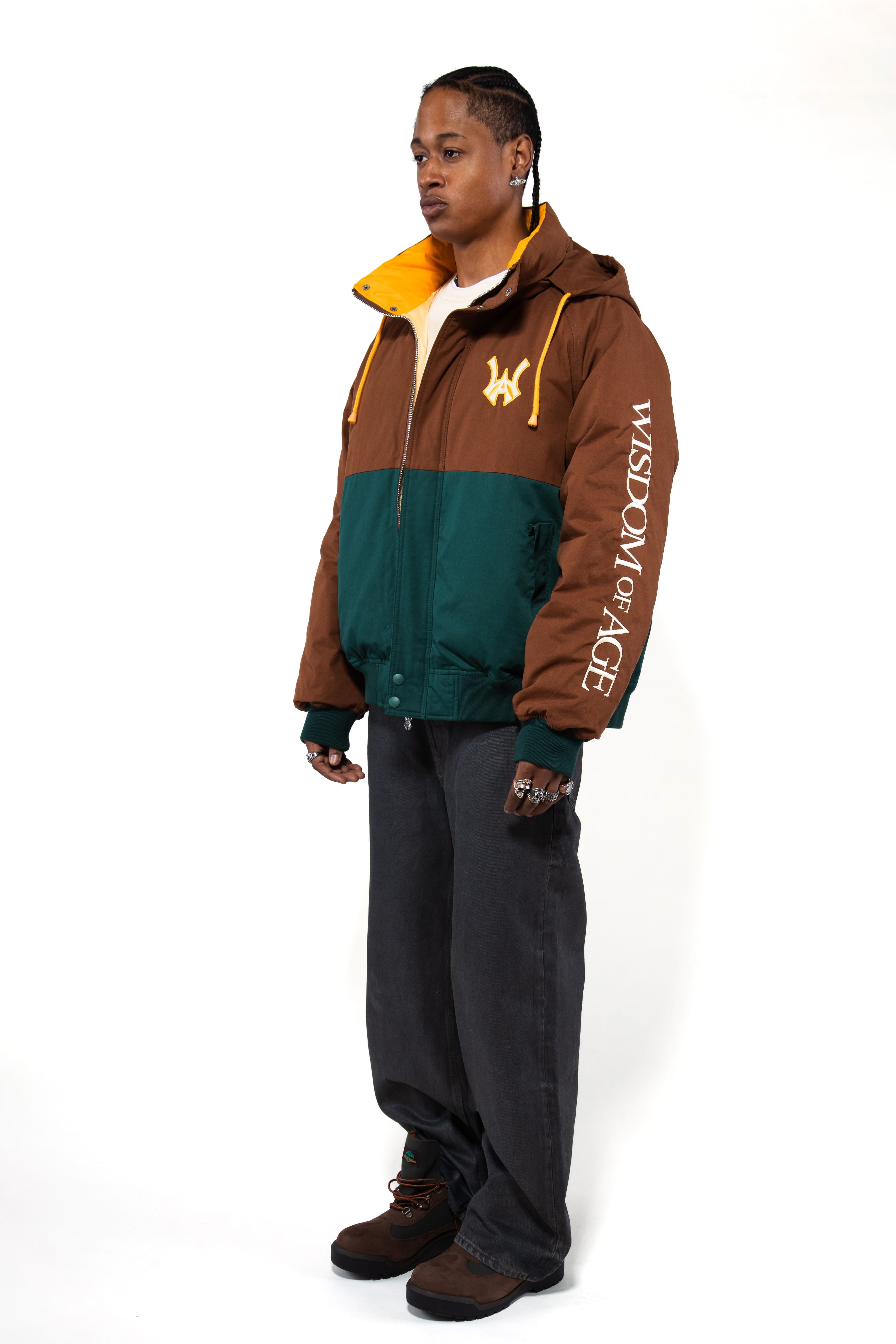 Side view of a Male Model wearing a brown and forest green jacket with yellow accents on a white background