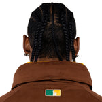 Close up Rear view of a Male Model wearing a brown with the 'NY Tough' logo embroidered on the neck. 