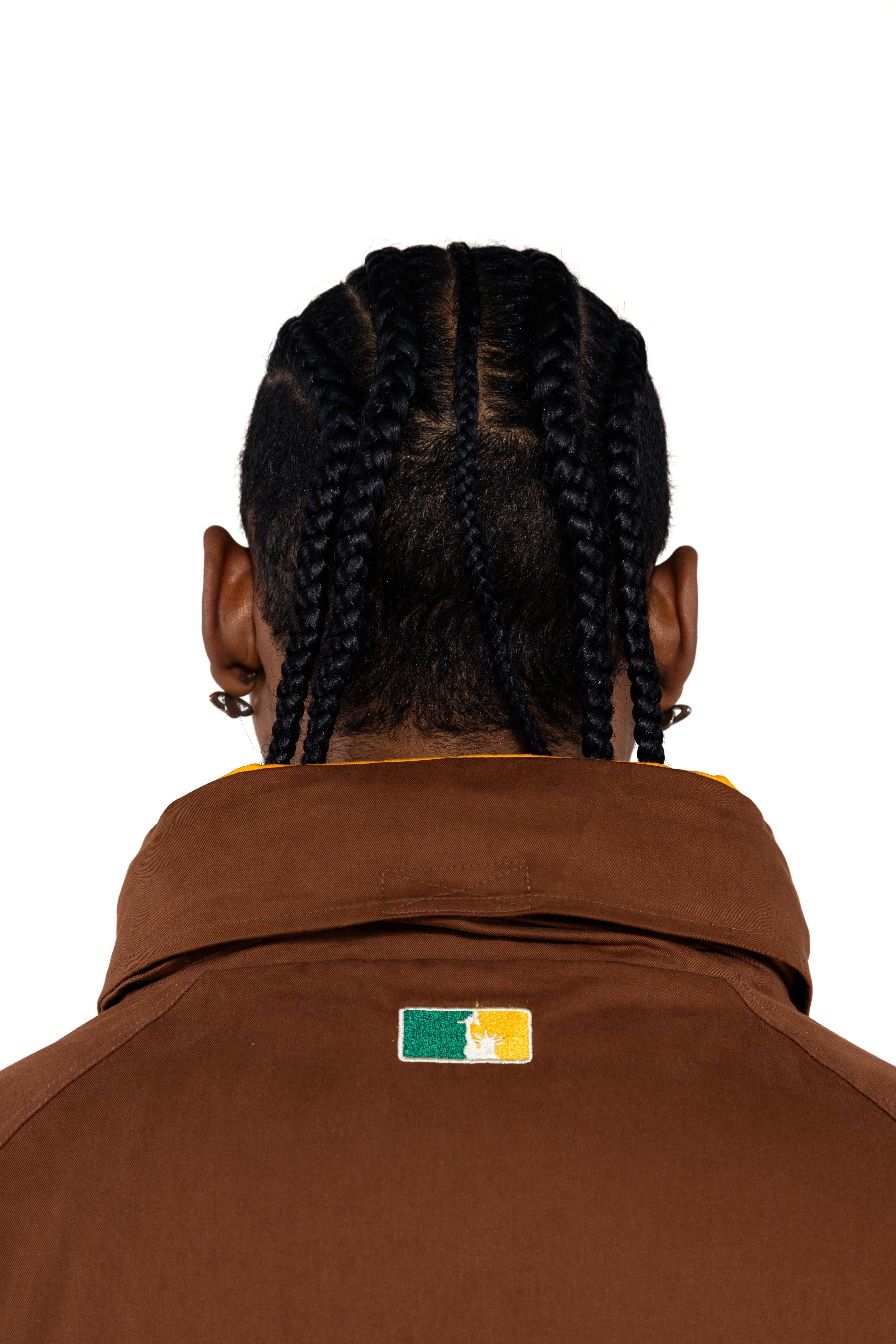 Close up Rear view of a Male Model wearing a brown with the 'NY Tough' logo embroidered on the neck. 