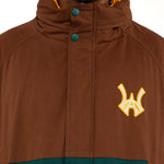 Close up view of a Male Model wearing a brown and forest green jacket with yellow accents on a white background. 'WA' Logo embroidered on the left chest.