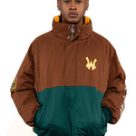 Close up view of a Male Model wearing a brown and forest green jacket with yellow accents on a white background. 'WA' Logo embroidered on the left 