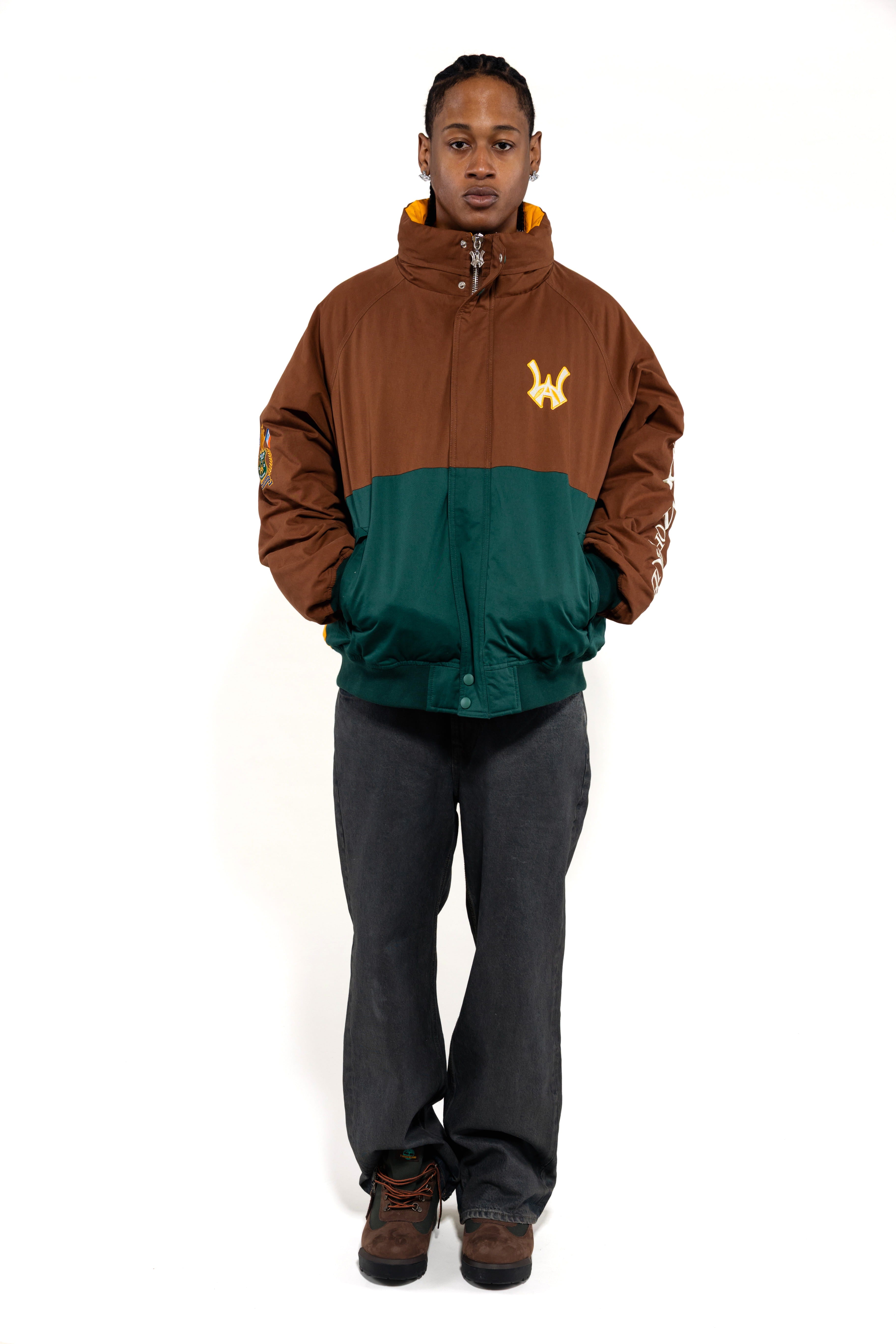 Male Model wearing a brown and green jacket with a embroidered 'WA' logo on a white background