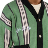Green cardigan with black and white striped pattern and 'Wisdom Of Age' branding.
