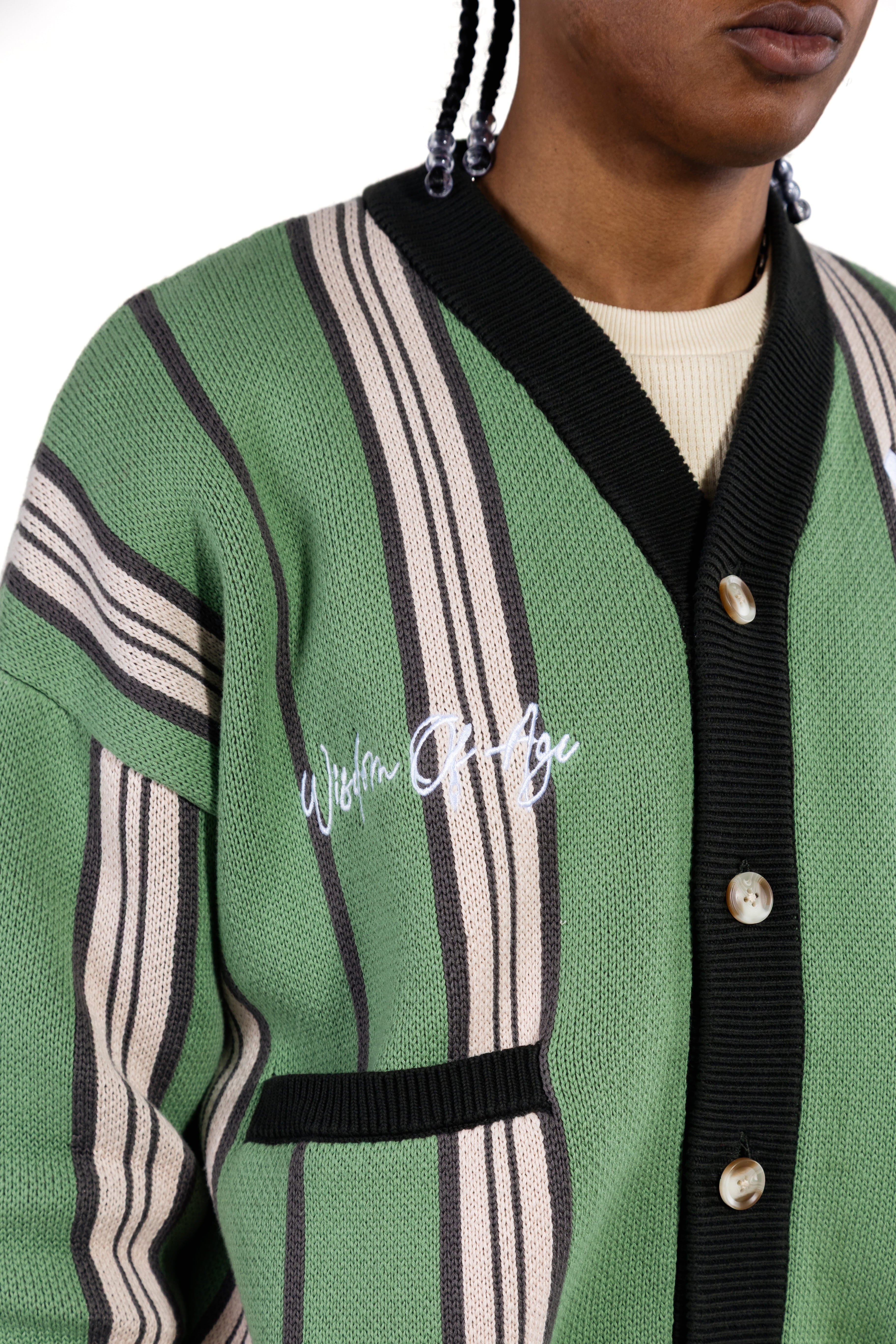 Green cardigan with black and white striped pattern and 'Wisdom Of Age' branding.
