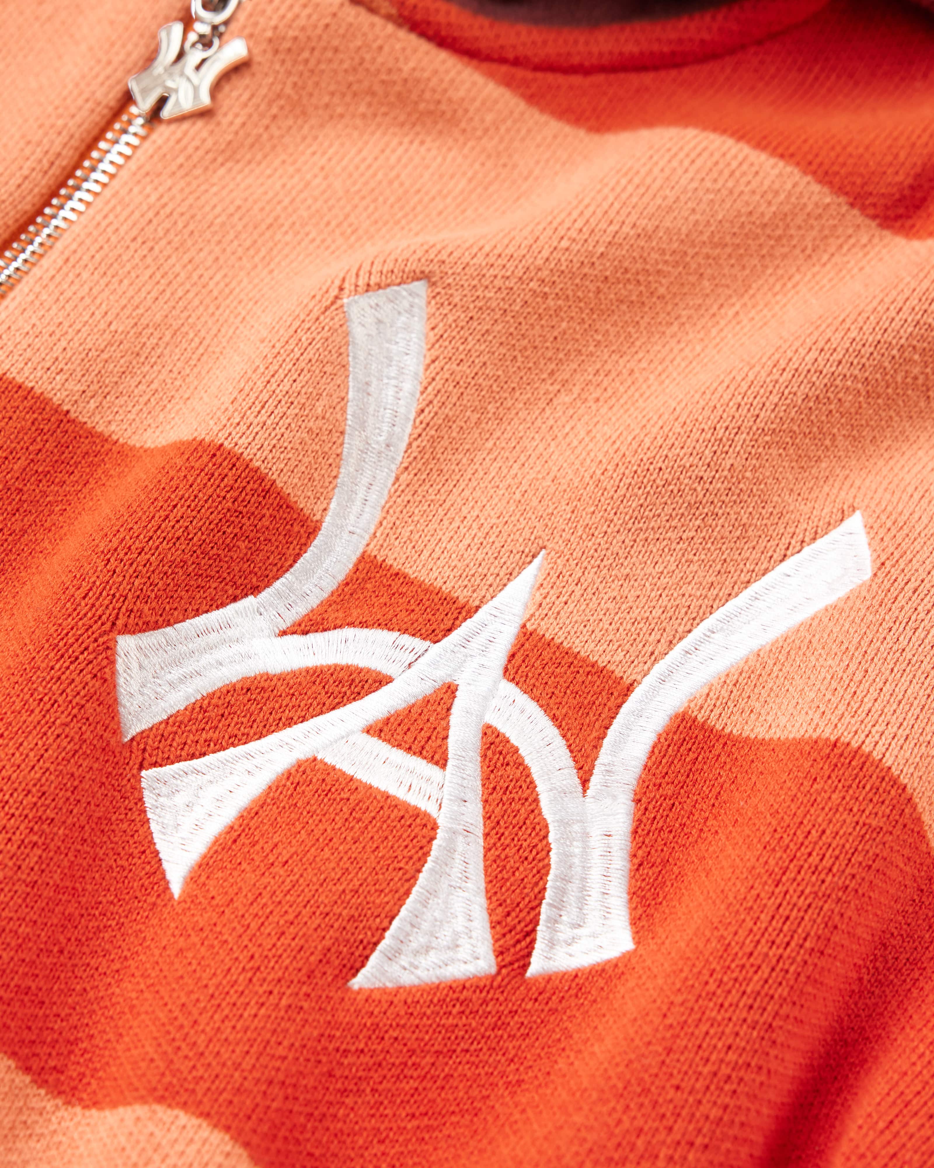 Close Up on the Front view of the WOA knit hoodie. WA logo embodied on the left chest in between the alternating orange stripes.