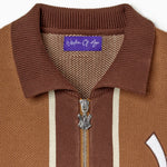 Close up view of the zipper and tag of the Wisdom Of Age Knitted Brown and beige striped cardigan on a white background.