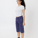 Side view of a Female model wearing a white t-shirt and Wisdom of age canvas carpenter shorts in purple color on a light gray background