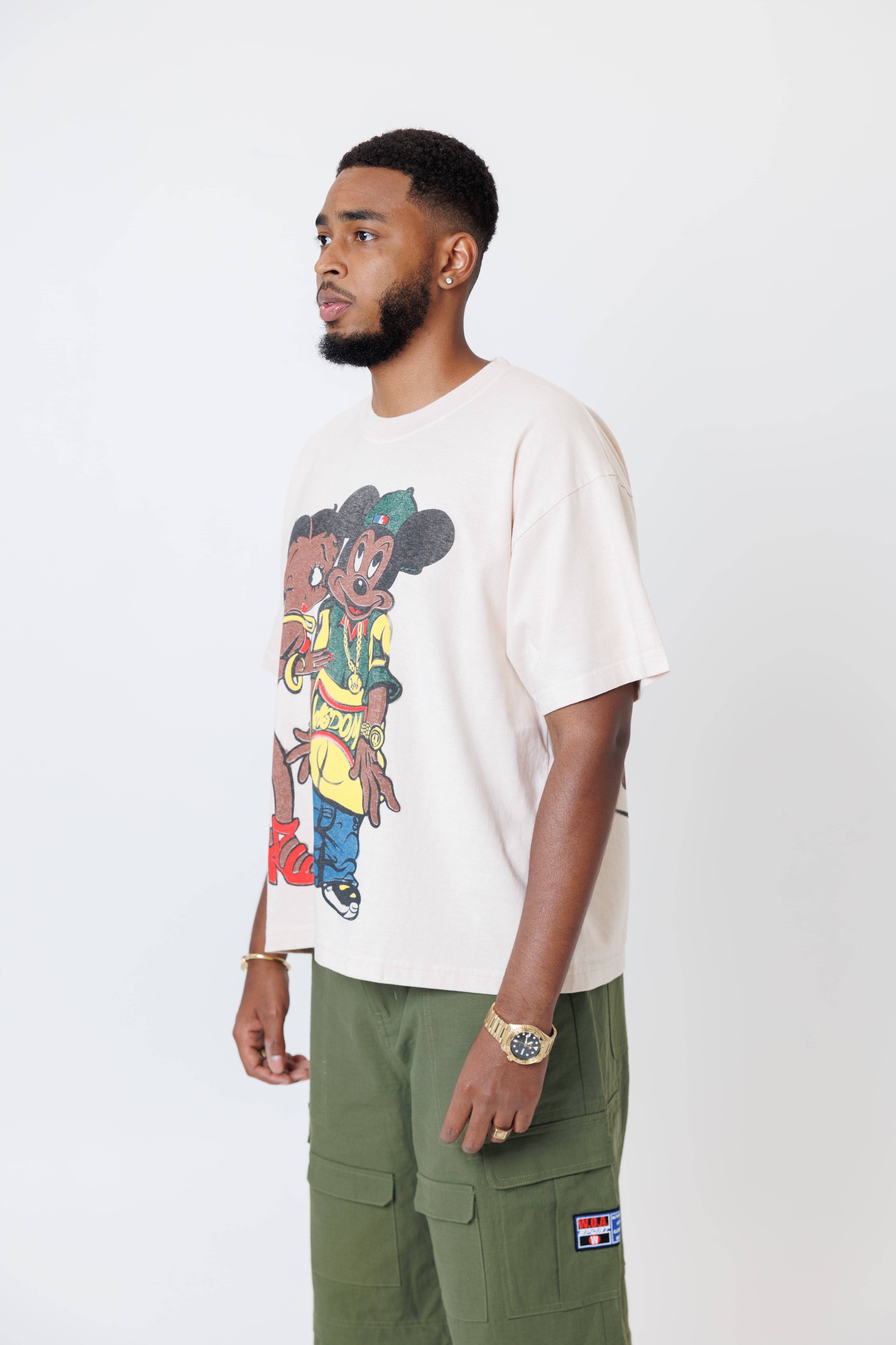 male model wearing a white t-shirt with cartoon characters and olive cargo pants on a light gray background