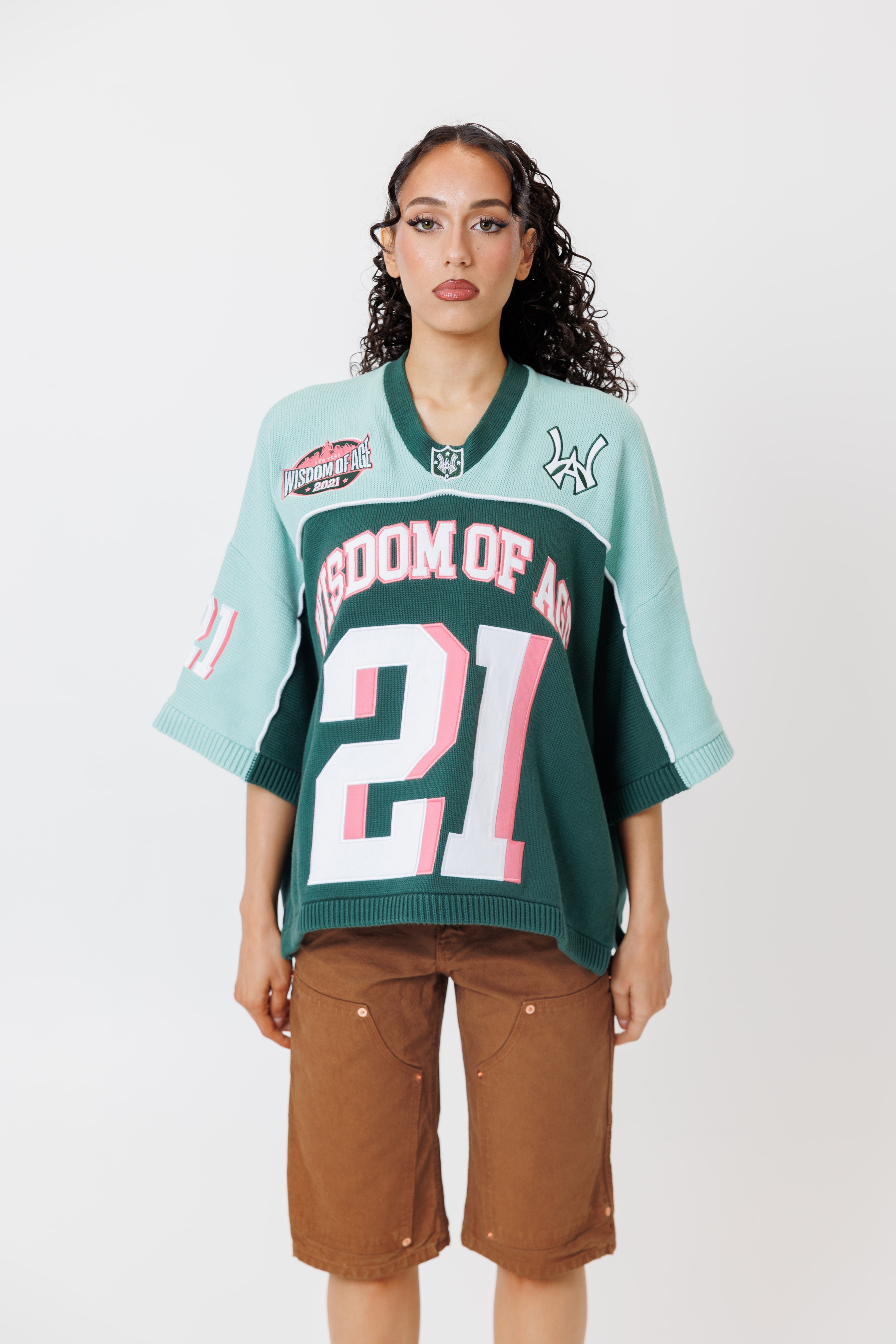 female Model wearing a the WOA Football jersey V2 in the Mint color with 'Wisdom Of Age' and number '21' embroidered on the front. Model is wearing the WOA canvas carpenter shorts on a white background.