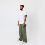 Side view of Male Model wearing a white t-shirt and the WOA Cargos in Olive color on a white background.