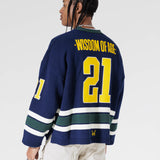 Reat View Of A Male Model wearing The Navy, Yellow and Green Wisdom Of Age Knit Hockey Jersey.