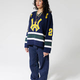 Full body Front View Of A Female Model wearing The Navy, Yellow and Green Wisdom Of Age Knit Hockey Jersey.