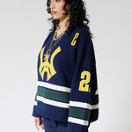 Front Side View Of A Female Model wearing The Navy, Yellow and Green Wisdom Of Age Knit Hockey Jersey.