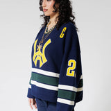 Front Side View Of A Female Model wearing The Navy, Yellow and Green Wisdom Of Age Knit Hockey Jersey.