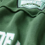 Close-up of a sage green football jersey with 'Wisdom of Age' branding