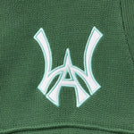 Close-up of a sage green fabric with a white WA logo on a textured background