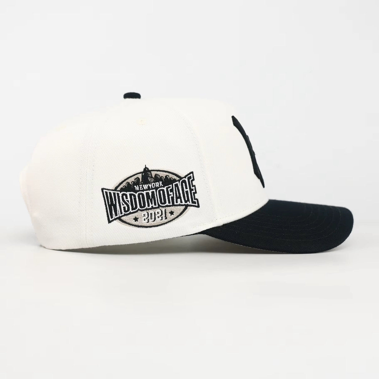White and black cap with 'Wisdom of Face' logo on a white background