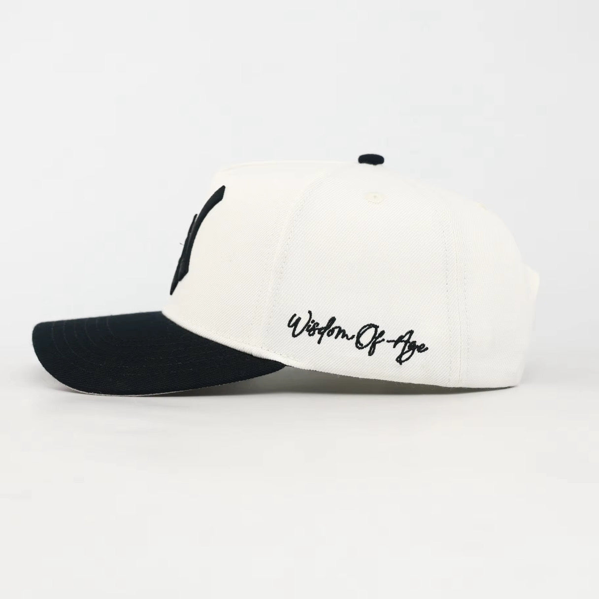 White and black cap with 'Wisdom of the Ages' text on a white background