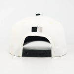 White and Black snapback cap with the WOA Liberty logo on the back against a white background