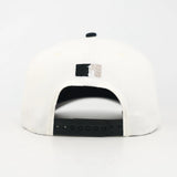 White and Black snapback cap with the WOA Liberty logo on the back against a white background
