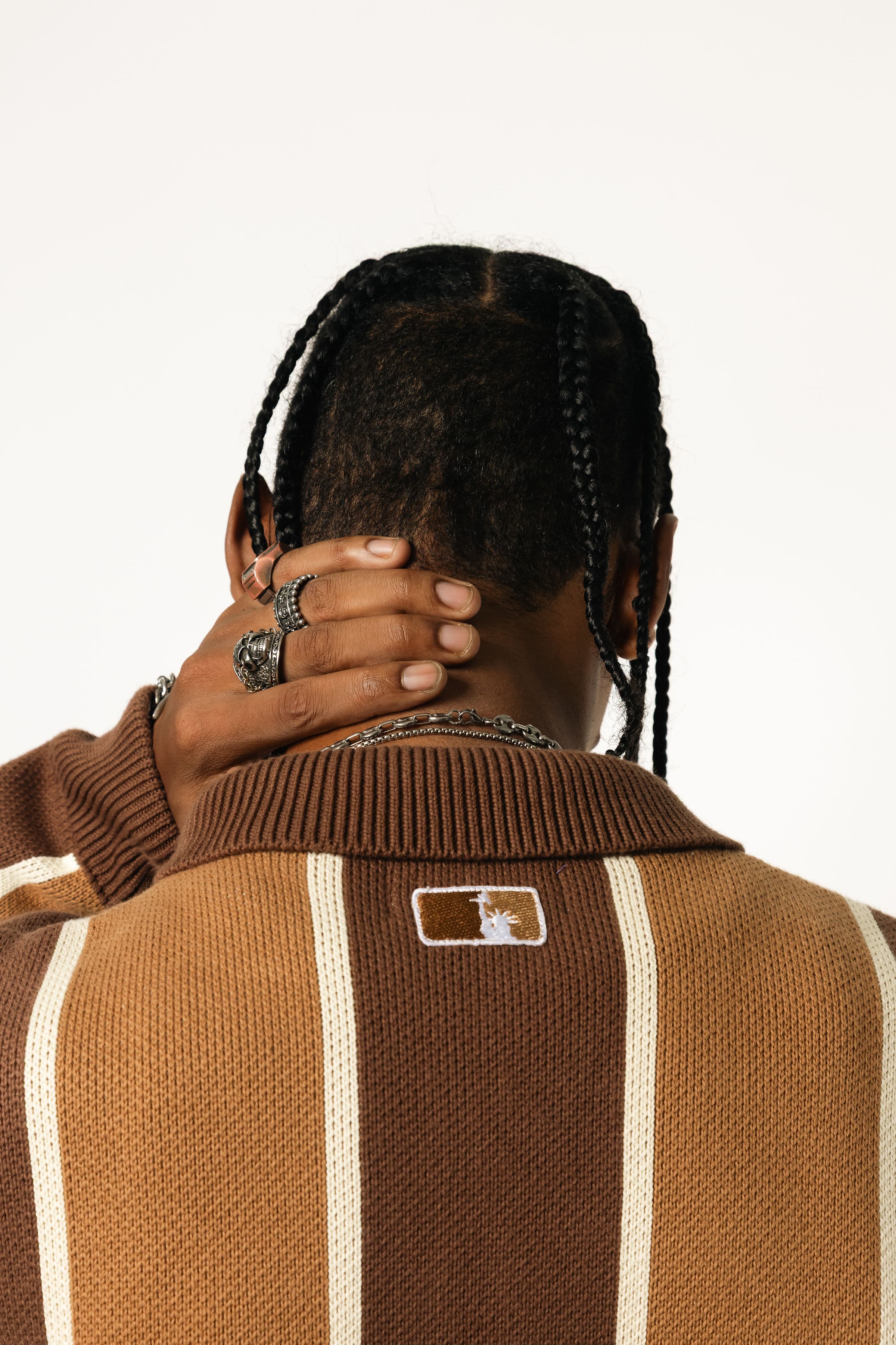 Close up rear view of a Male model wearing the WOA Knitted Brown and beige striped cardigan  on a white background.