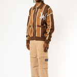 full body photo of a Male model wearing the WOA Knitted Brown and beige striped cardigan with WA logo on the left chest and 'Wisdom Of Age' written in script on the right chest on a white background.