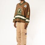 Full body photo of a Male Model wearing the WOA Knitted Hockey Jersey with Embroidered WA logo, Captains patch and W.O.A liberty graphic standing against a white background.