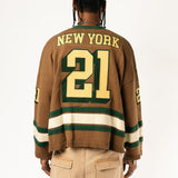 Rear view of a male Model wearing the WOA Knitted Hockey Jersey with Embroidered 'NEW YORK' and the number 21 standing against a white background.
