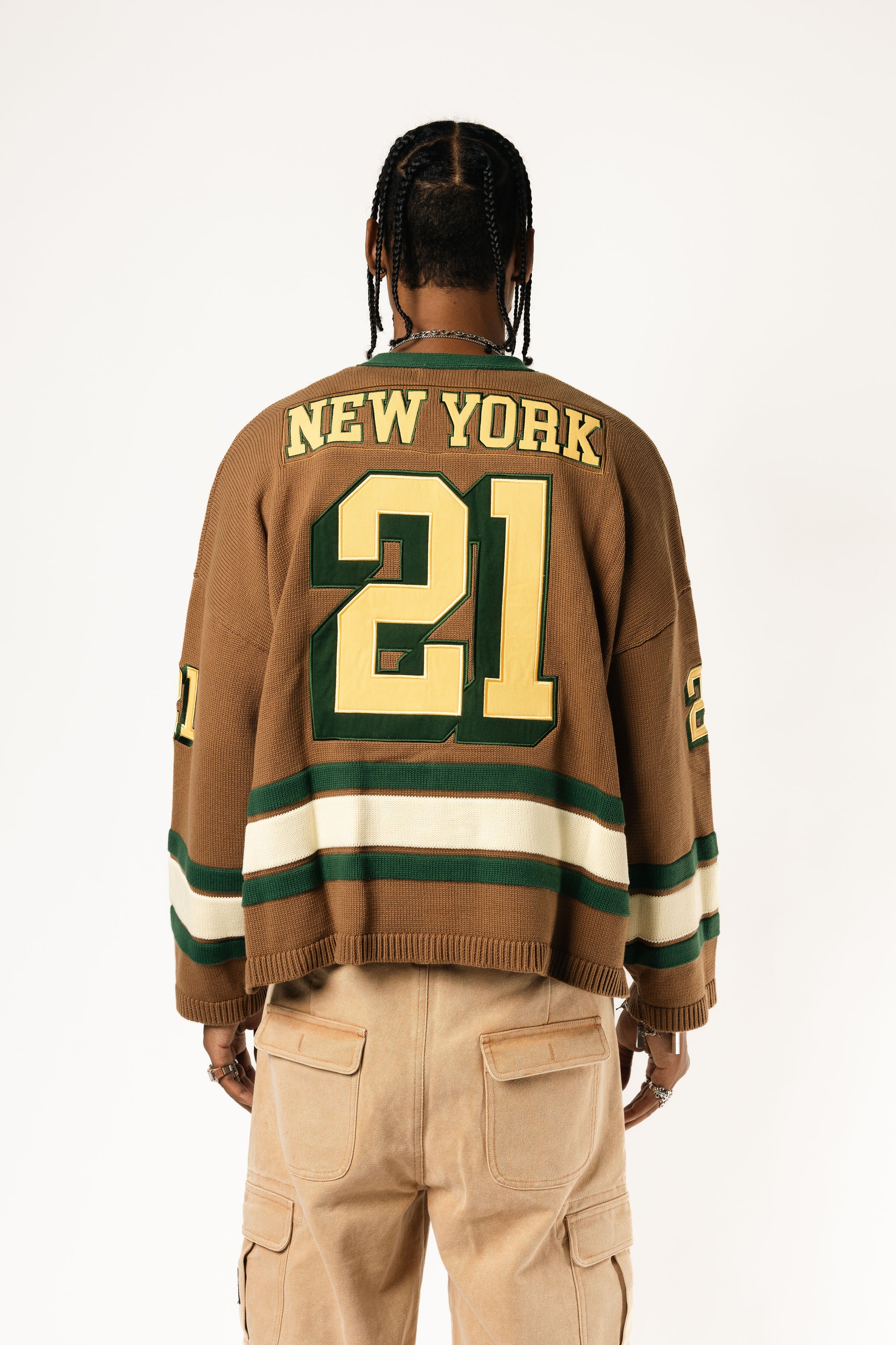 Rear view of a male Model wearing the WOA Knitted Hockey Jersey with Embroidered 'NEW YORK' and the number 21 standing against a white background.