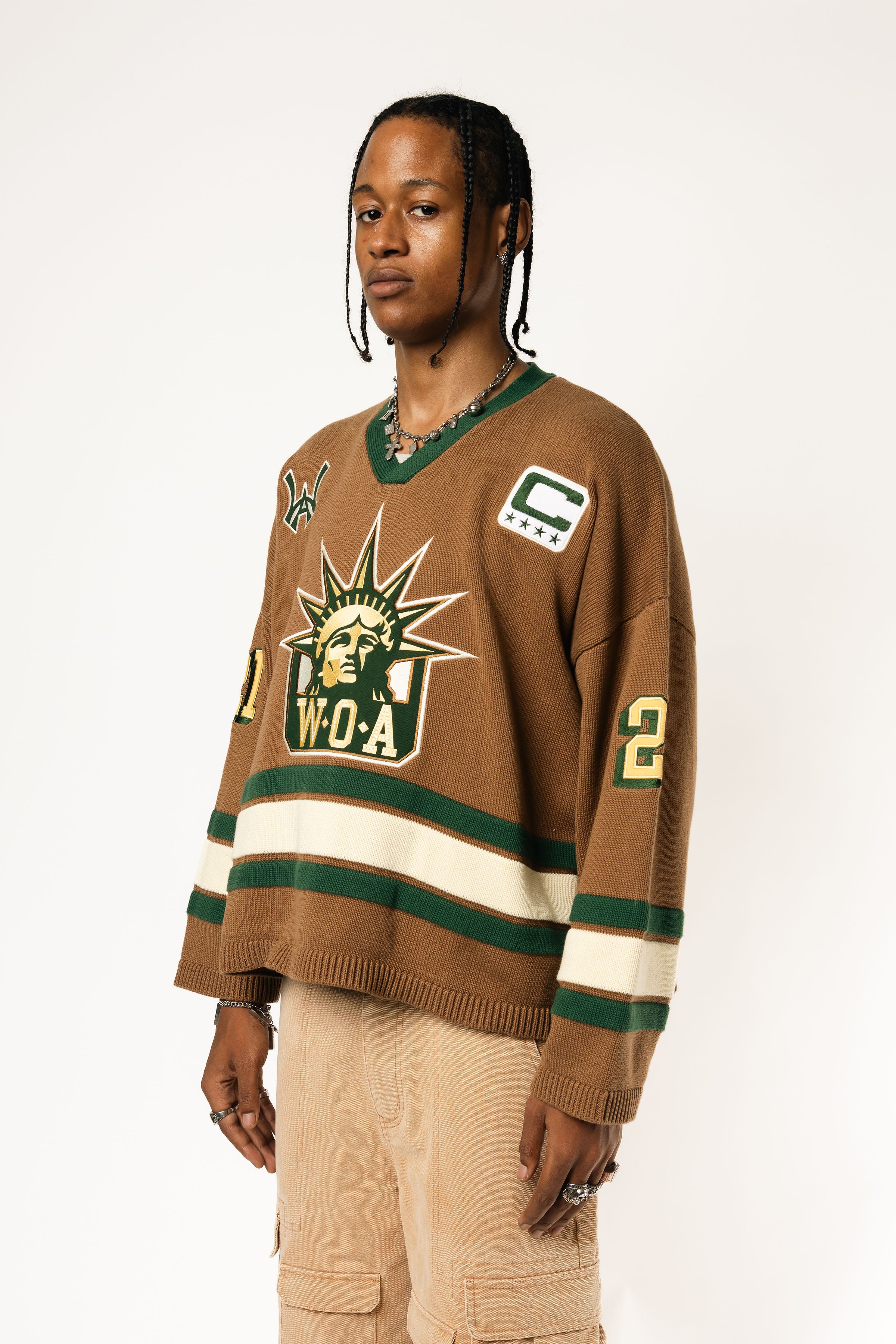 Front-side view of a Male Model wearing the WOA Knitted Hockey Jersey with Embroidered WA logo, Captains patch and W.O.A liberty graphic standing against a white background.