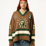 Female Model wearing the WOA Knitted Hockey Jersey with Embroidered WA logo, Captains patch and W.O.A liberty graphic standing against a white background.