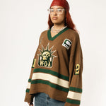 Front-side view of a Female Model wearing the WOA Knitted Hockey Jersey with Embroidered WA logo, Captains patch and W.O.A liberty graphic standing against a white background.
