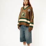 Full body view of a Female Model wearing the WOA Knitted Hockey Jersey with Embroidered WA logo, Captains patch and W.O.A liberty graphic standing against a white background.